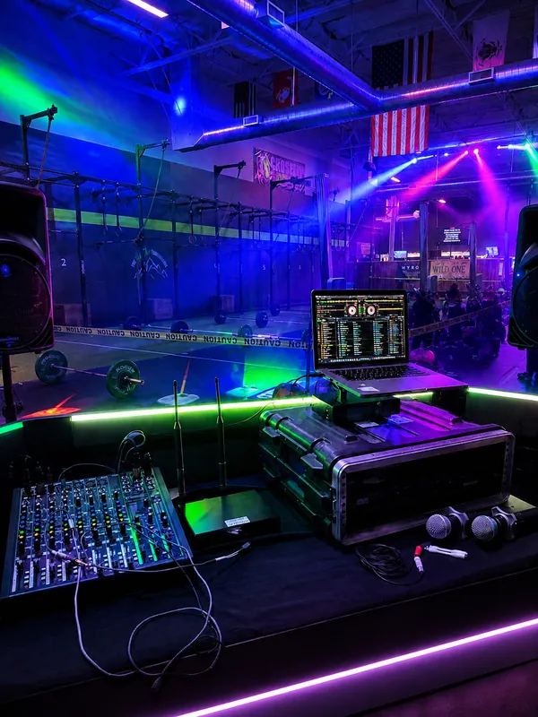 The rig in a gym under blue and violet light, the mixer and decks lit up