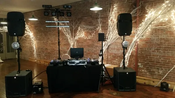 The rig set up against a brick wall, speakers on stands and sparkle lights behind the booth