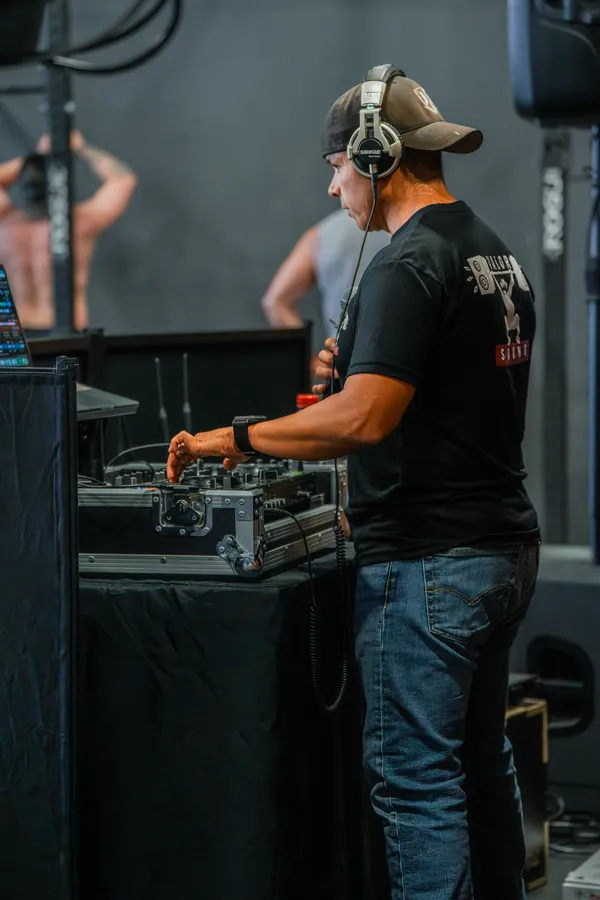 Hector in headphones at the decks beside the rig at a fitness competition