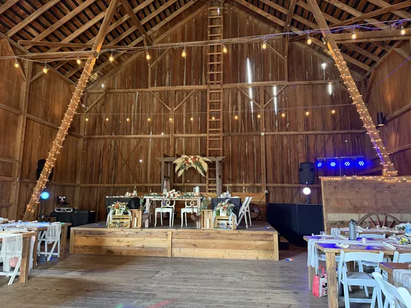 Barn venue set for a reception with string lights and the booth by the head table