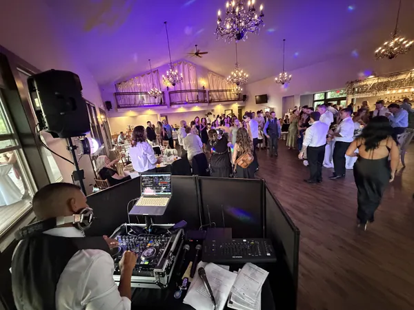 A packed dance floor under chandeliers and violet light